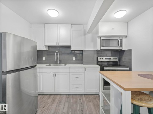 Kitchen with stainless steel appliances, butcher block countertops, white cabinetry, and light wood-style flooring - 1404 Podersky Link, Edmonton, AB - Indoor Photo Showing Kitchen