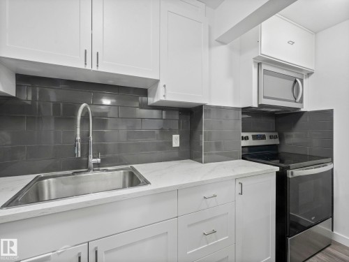 Kitchen with stainless steel appliances, decorative backsplash, and white cabinetry - 1404 Podersky Link, Edmonton, AB - Indoor Photo Showing Kitchen