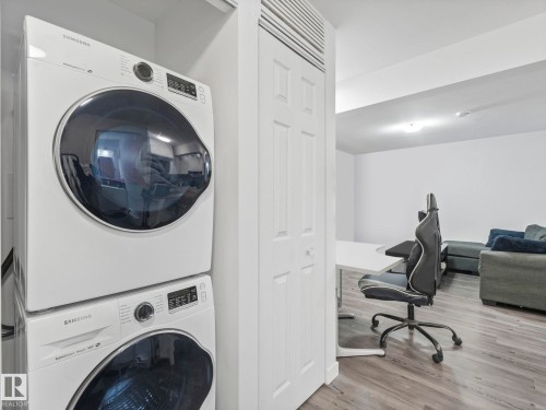 Laundry area with stacked washer and dryer, light wood-style floors, and an office area - 1404 Podersky Link, Edmonton, AB - Indoor Photo Showing Laundry Room