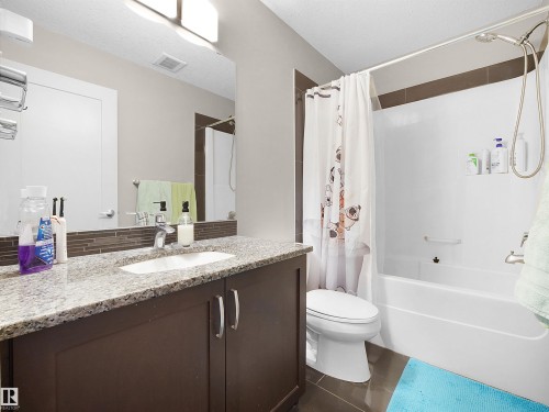 Full bath featuring vanity, shower / bath combination with curtain, and dark tile patterned flooring - 1659 Hammond Crescent, Edmonton, AB - Indoor Photo Showing Bathroom