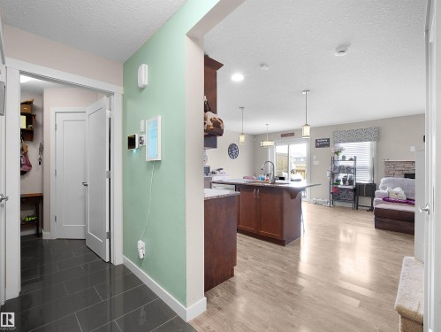 Kitchen with a textured ceiling, a center island with sink, hanging light fixtures, a kitchen breakfast bar, and light wood-style floors - 1659 Hammond Crescent, Edmonton, AB - Indoor