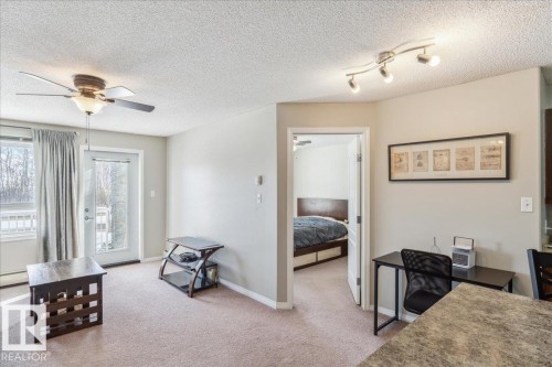 Bedroom with access to exterior, light colored carpet, a textured ceiling, an office area, and a ceiling fan - 112 5340 199 Street, Edmonton, AB - Indoor