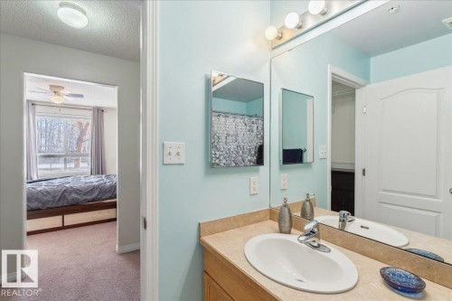 Ensuite bathroom with vanity, a textured ceiling, light colored carpet, ceiling fan, and curtained shower - 112 5340 199 Street, Edmonton, AB - Indoor Photo Showing Bathroom
