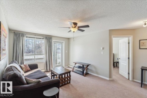 Living area with light colored carpet, a ceiling fan, and a textured ceiling - 112 5340 199 Street, Edmonton, AB - Indoor Photo Showing Living Room