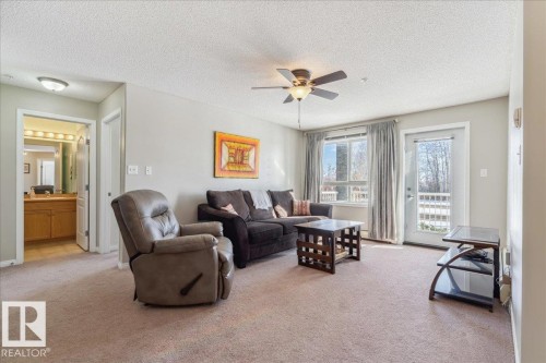Living room with ceiling fan, light carpet, and a textured ceiling - 112 5340 199 Street, Edmonton, AB - Indoor Photo Showing Living Room