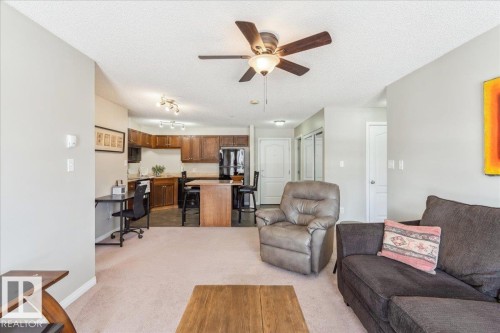 Living area featuring ceiling fan, light carpet, a textured ceiling, and an office area - 112 5340 199 Street, Edmonton, AB - Indoor Photo Showing Living Room