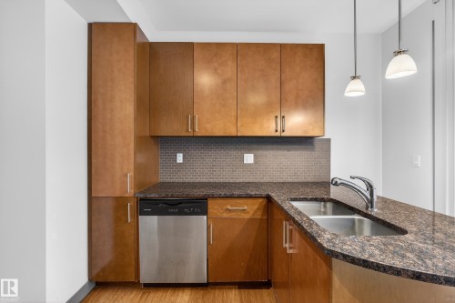 Kitchen featuring wooden cabinetry, a stainless steel dishwasher, a double basin sink, and pendant lighting - 1649 Cunningham Way, Edmonton, AB - Indoor Photo Showing Kitchen With Double Sink