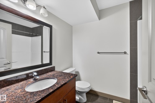 The bathroom features a vanity with a brown granite countertop and an oval sink, a wall-mounted mirror, and overhead lighting - 1649 Cunningham Way, Edmonton, AB - Indoor Photo Showing Bathroom