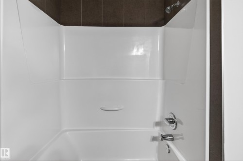 The bathroom features a white bathtub and shower combination with chrome fixtures - 1649 Cunningham Way, Edmonton, AB - Indoor Photo Showing Bathroom