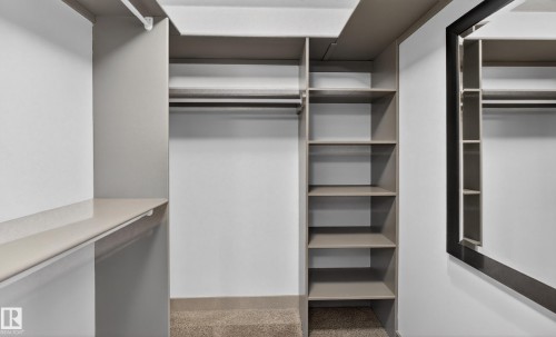 The closet features built-in shelving, hanging rods, and a full-length mirror - 1649 Cunningham Way, Edmonton, AB - Indoor With Storage