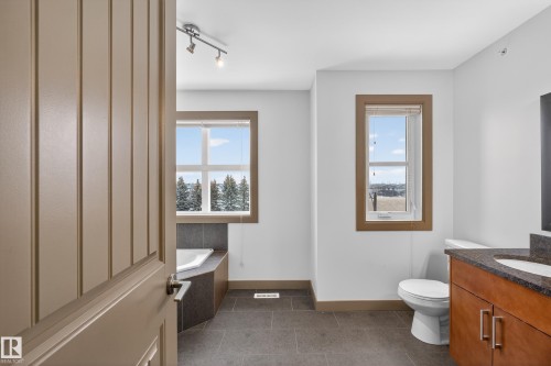 The bathroom features a built-in corner bathtub, a single vanity with a granite countertop, and a toilet - 1649 Cunningham Way, Edmonton, AB - Indoor Photo Showing Bathroom