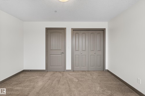 The room features neutral-toned carpet, white walls, and a ceiling light fixture - 1649 Cunningham Way, Edmonton, AB - Indoor Photo Showing Other Room