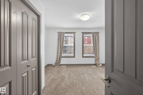 This room features plush carpet flooring, white walls, and two windows with blinds and curtains - 1649 Cunningham Way, Edmonton, AB - Indoor Photo Showing Other Room