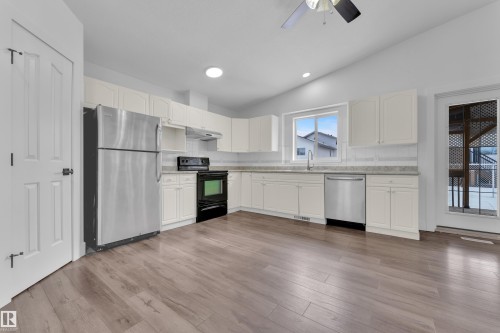 Kitchen featuring stainless steel appliances, vaulted ceiling, white cabinets, a ceiling fan, and backsplash - 6741 162A Avenue, Edmonton, AB - Indoor Photo Showing Kitchen