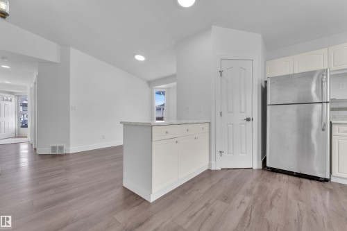 Kitchen with freestanding refrigerator, white cabinets, a peninsula, lofted ceiling, and light wood-style flooring - 6741 162A Avenue, Edmonton, AB - Indoor Photo Showing Other Room