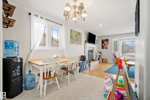 Rec room with healthy amount of natural light, hanging lights, a glass covered fireplace, and light tile patterned floors - 9221 84 Street, Fort Saskatchewan, AB - Indoor Photo Showing Dining Room