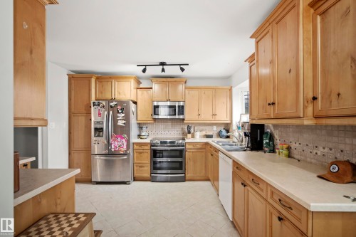Kitchen with stainless steel appliances, light countertops, light tile patterned flooring, decorative backsplash, and track lighting - 9221 84 Street, Fort Saskatchewan, AB - Indoor Photo Showing Kitchen With Double Sink