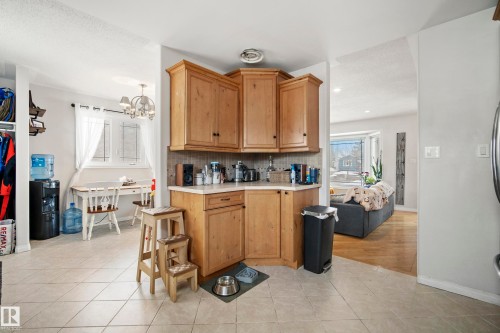Kitchen with light countertops, light tile patterned floors, a chandelier, tasteful backsplash, and wood finish cabinets - 9221 84 Street, Fort Saskatchewan, AB - Indoor Photo Showing Other Room