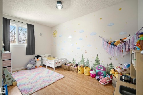 Bedroom featuring a crib, a textured ceiling, and light wood-style floors - 9221 84 Street, Fort Saskatchewan, AB - Indoor Photo Showing Bedroom