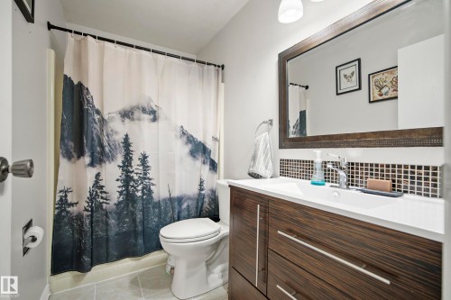Bathroom with vanity, light tile patterned flooring, shower / bath combination with curtain, and tasteful backsplash - 9221 84 Street, Fort Saskatchewan, AB - Indoor Photo Showing Bathroom