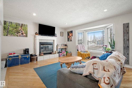 Living room featuring recessed lighting, light wood finished floors, a tile fireplace, and a textured ceiling - 9221 84 Street, Fort Saskatchewan, AB - Indoor Photo Showing Living Room With Fireplace