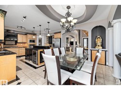 Dining space featuring a chandelier, beverage cooler, light tile patterned floors, arched walkways, and a raised ceiling - 