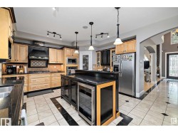 Kitchen with arched walkways, light wood finish cabinetry, wine cooler, and light tile patterned floors - 