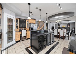 Two tone kitchen featuring light tile patterned flooring, a kitchen island, stainless steel appliances, arched walkways, and hanging lights - 