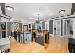 Hall with a chandelier, a skylight, hardwood / wood-style floors, a textured ceiling, and an upstairs landing - 