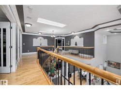 Hall with an upstairs landing, light wood-type flooring, a skylight, and a textured ceiling - 
