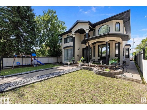 View of front of home with a fenced backyard, a playground, stucco siding, and a patio - 9544 154 Street, Edmonton, AB 