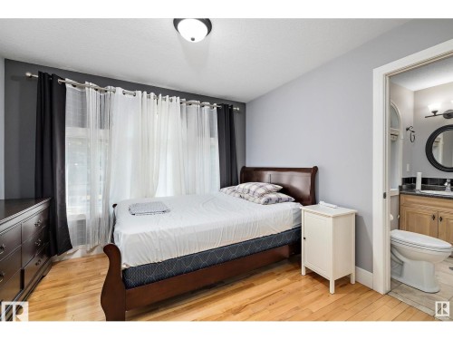 Bedroom with light wood-style floors, a textured ceiling, and ensuite bath - 9544 154 Street, Edmonton, AB 