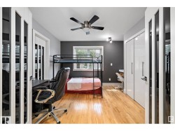 Bedroom with a desk, light wood-type flooring, and a ceiling fan - 