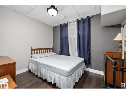 Bedroom featuring a paneled ceiling and dark wood-style flooring - 