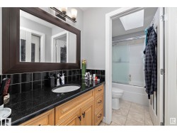 Full bath featuring vanity, bath / shower combo with glass door, light tile patterned flooring, and a skylight - 