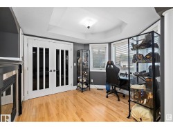 Office space with a tray ceiling, light wood finished floors, and french doors - 