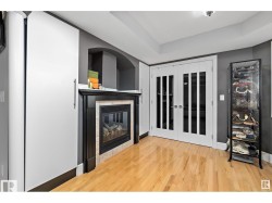 Unfurnished living room with light wood-style flooring, a tile fireplace, french doors, and a raised ceiling - 