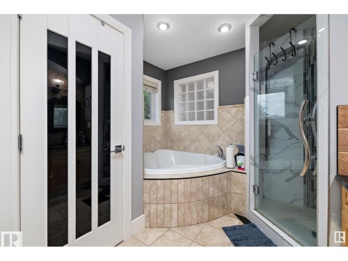Full bathroom featuring a bath, a marble finish shower, and light tile patterned floors - 9544 154 Street, Edmonton, AB 