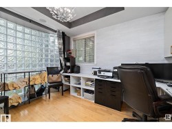 Office area with light wood-style flooring, a tray ceiling, and hanging lights - 