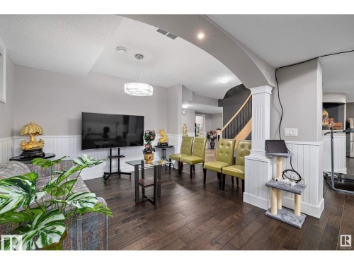 Living room featuring wainscoting, arched walkways, dark wood-type flooring, and a decorative wall - 9544 154 Street, Edmonton, AB 