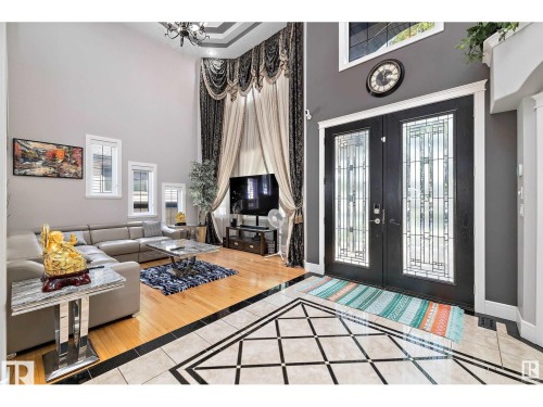 Foyer featuring inlaid floor details, french doors, healthy amount of natural light, a high ceiling, and light tile patterned floors - 9544 154 Street, Edmonton, AB 
