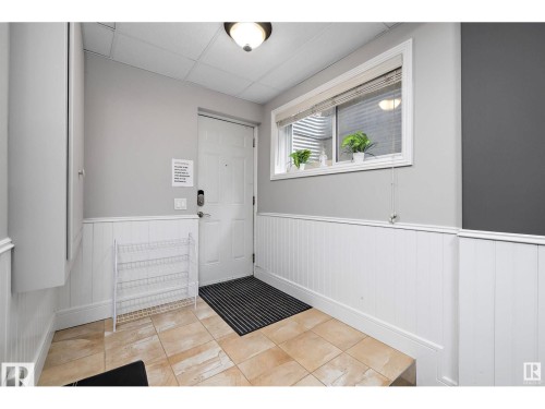 Entrance foyer featuring light tile patterned flooring, a wainscoted wall, and a paneled ceiling - 9544 154 Street, Edmonton, AB 