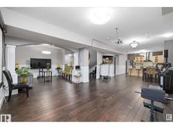 Living area featuring dark wood-type flooring, a textured ceiling, arched walkways, a wainscoted wall, and decorative columns - 