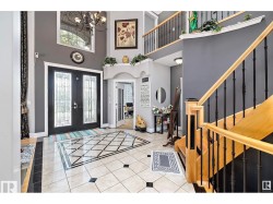 Entryway with french doors, suspended lighting, light tile patterned floors, a high ceiling, and arched walkways - 