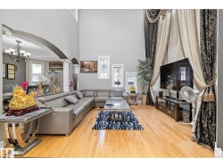 Living room with arched walkways, suspended lighting, light wood finished floors, and a high ceiling - 