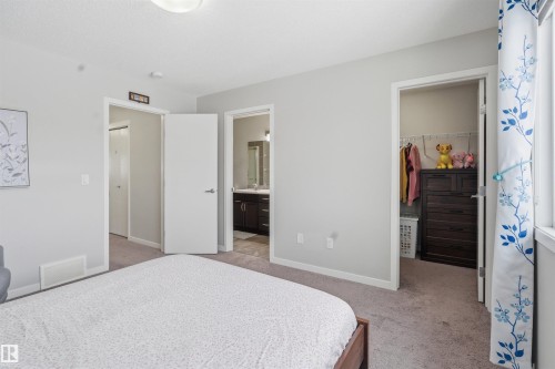Bedroom with a spacious closet, light colored carpet, and connected bathroom - 5112 Andison Close, Edmonton, AB - Indoor Photo Showing Bedroom