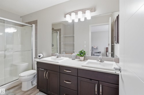 Full bath featuring double vanity, a shower stall, connected bathroom, and light wood-type flooring - 5112 Andison Close, Edmonton, AB - Indoor Photo Showing Bathroom