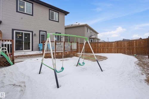 Snow covered playground featuring a deck, a fenced backyard, and a playground - 5112 Andison Close, Edmonton, AB - Outdoor With Exterior