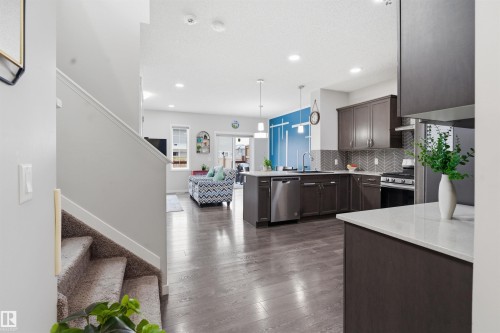Kitchen with dark wood finish cabinets, stainless steel appliances, pendant lighting, a peninsula, and dark wood-style floors - 5112 Andison Close, Edmonton, AB - Indoor Photo Showing Kitchen With Upgraded Kitchen