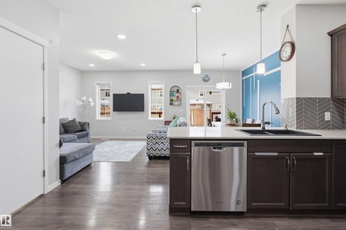Kitchen with dark wood finish cabinetry, a peninsula, stainless steel dishwasher, dark wood-type flooring, and a textured ceiling - 5112 Andison Close, Edmonton, AB - Indoor Photo Showing Kitchen With Double Sink With Upgraded Kitchen